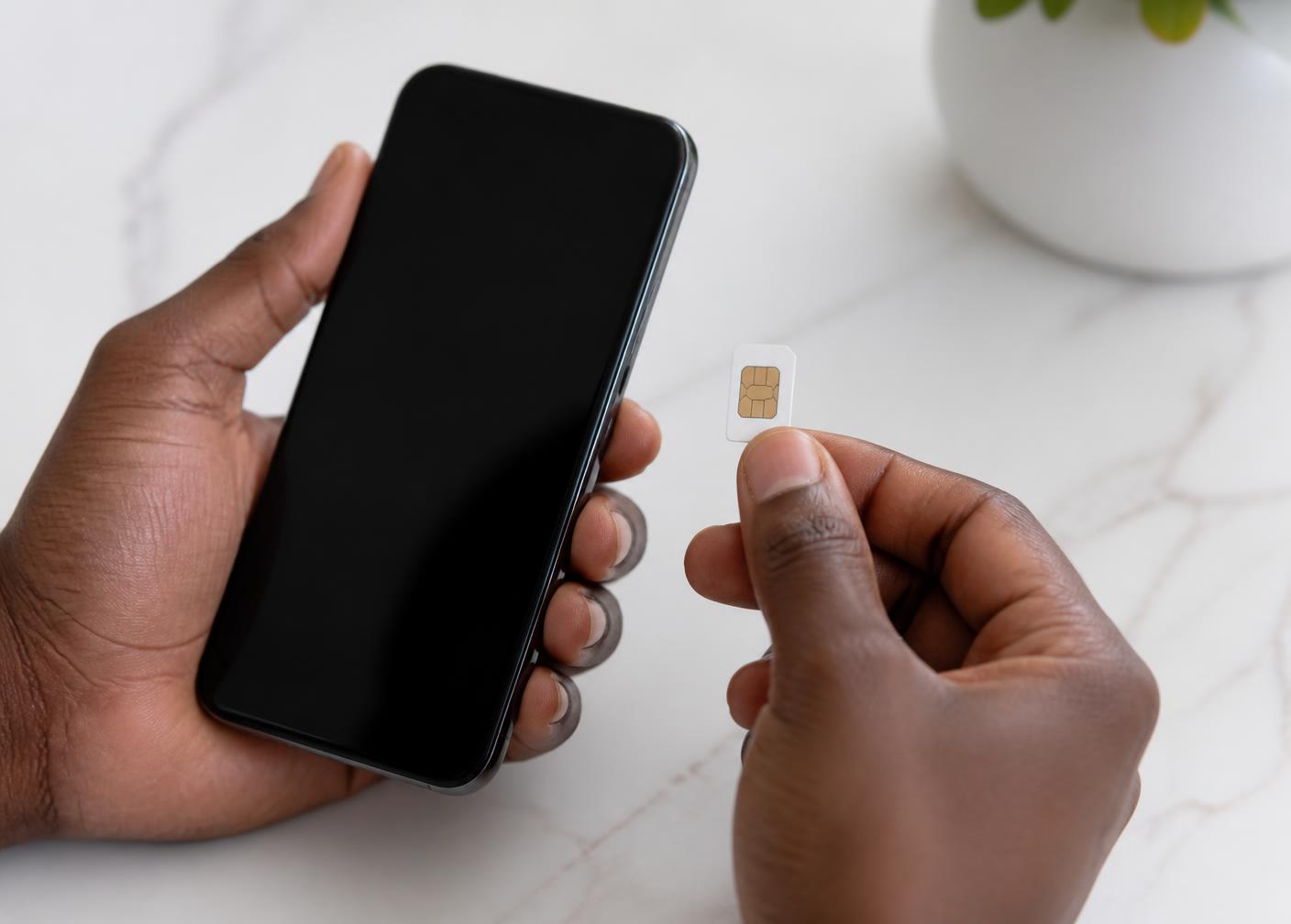 Une main tient une carte SIM à côté d'un smartphone